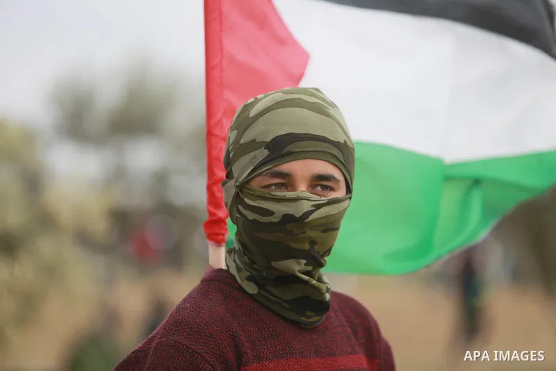 A masked Palestinian protester takes part during a tent city protest along the Israel border with Gaza, demanding the right to return to their homeland, east of Gaza City March 30, 2018. Photo by Mohammed Dahman
