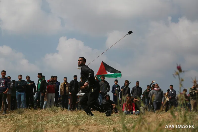A Palestinian protester uses a slingshot to hurl stones toward Israeli security forces during clashes in a tent city protest along the Israel border with Gaza, demanding the right to return to their homeland, east of Gaz...