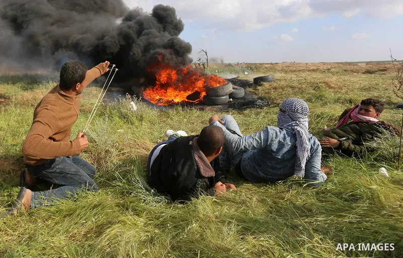 A Palestinian protester uses a slingshot to hurl stones towards Isareli security forces during clashes in a tent city protest at along the Israel border with Gaza, demanding the right to return to their homeland, in al-B...