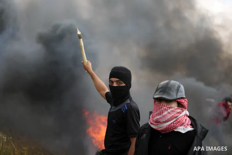 A masked Palestinian protester holds axe during clashes with Israeli security forces in a tent city protest along the Israel border with Gaza, demanding the right to return to their homeland, in Khan Younis in the southe...
