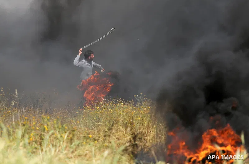 A Palestinian protester uses a slingshot to hurl stones towards Israeli security forces during clashes in a tent city protest along the Israel border with Gaza, demanding the right to return to their homeland, in Khan Yo...