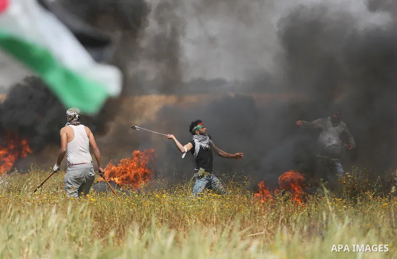 A Palestinian protester uses a slingshot to hurl stones towards Israeli security forces during clashes in a tent city protest along the Israel border with Gaza, demanding the right to return to their homeland, in Khan Yo...