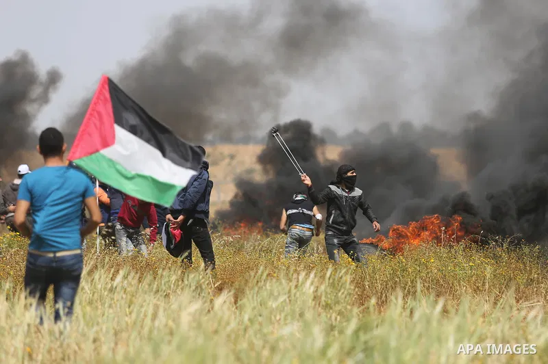 A Palestinian protester uses a slingshot to hurl stones towards Israeli security forces during clashes in a tent city protest along the Israel border with Gaza, demanding the right to return to their homeland, in Khan Yo...