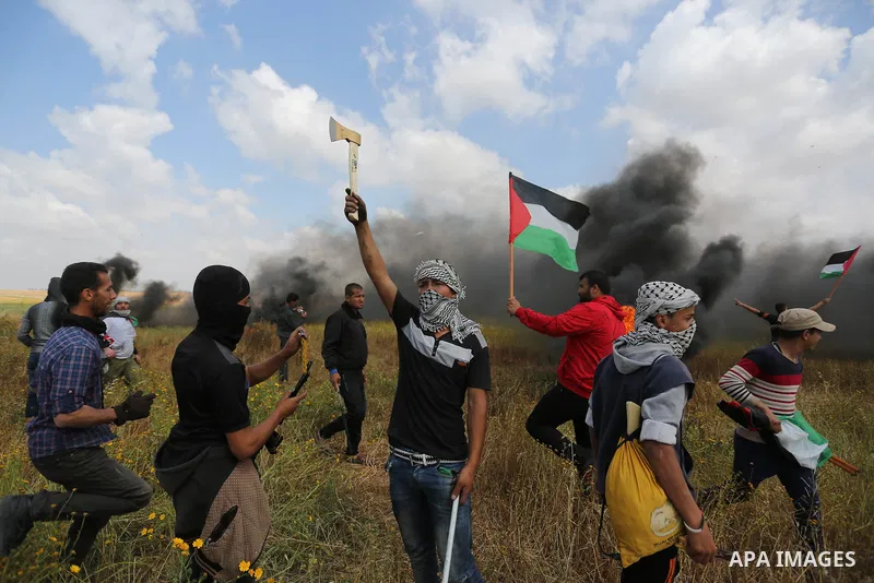 A masked Palestinian protester holds axe during clashes with Israeli security forces in a tent city protest along the Israel border with Gaza, demanding the right to return to their homeland, in Khan Younis in the southe...