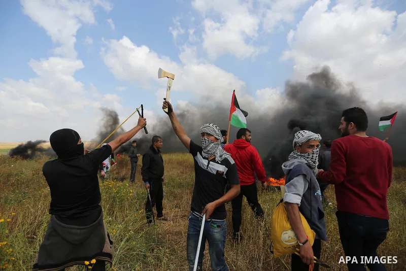 A masked Palestinian protester holds axe during clashes with Israeli security forces in a tent city protest along the Israel border with Gaza, demanding the right to return to their homeland, in Khan Younis in the southe...