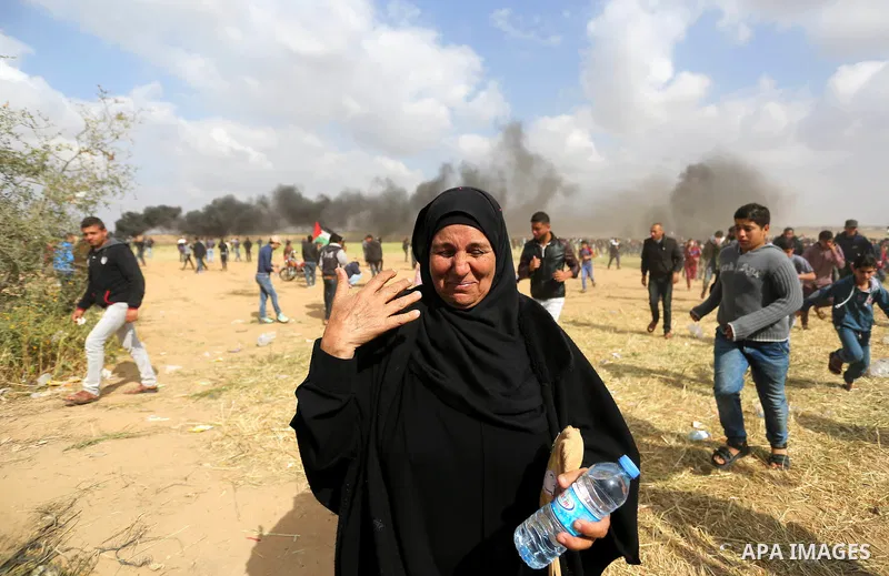 A Palestinian woman reacts from tear gas fired by Israeli security forces during clashes, in a tent city protest along the Israel border with Gaza, demanding the right to return to their homeland, in Khan Younis in the s...