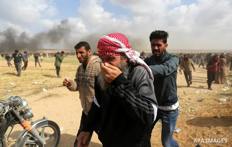 Palestinians react from tear gas fired by Israeli security forces during clashes, in a tent city protest along the Israel border with Gaza, demanding the right to return to their homeland, in Khan Younis in the southern...