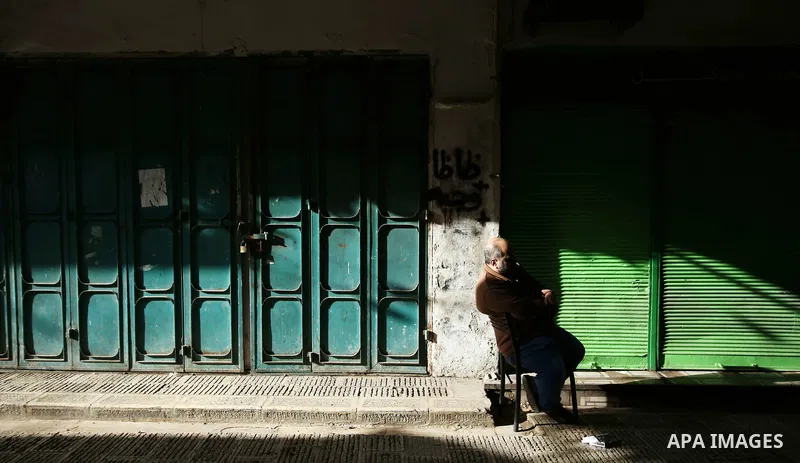 A Palestinian man sits outside closed shops in the empty streets of the Israeli occupied West Bank city of Nablus during a general strike called for by local leaders in solidarity with Gaza to mourn for the 15 Palestinia...