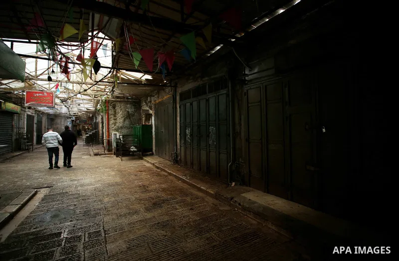 Palestinians walk past closed shops in the empty streets of the Israeli occupied West Bank city of Nablus during a general strike called for by local leaders in solidarity with Gaza to mourn for the 15 Palestinians who w...