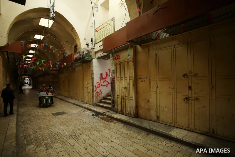 A Palestinians vendor walks past closed shops in the empty streets of the Israeli occupied West Bank city of Nablus during a general strike called for by local leaders in solidarity with Gaza to mourn for the 15 Palestin...