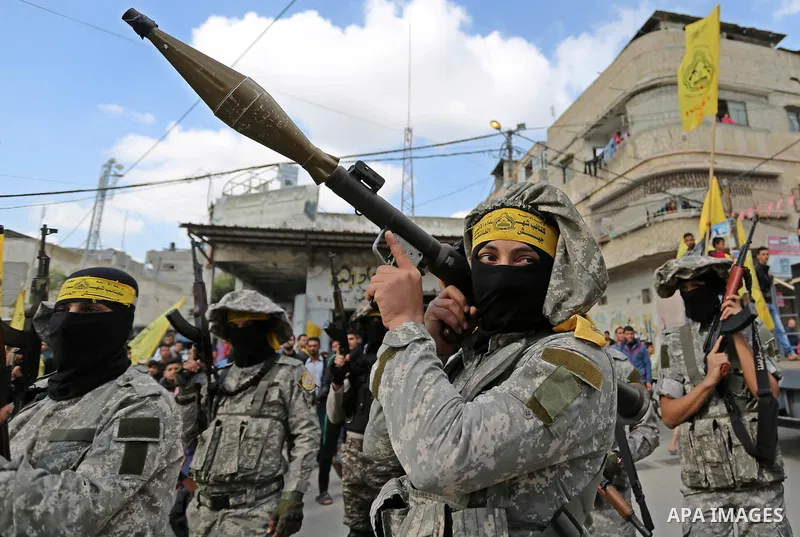Palestinian militants of Al-Aqsa Martyrs' Brigades attend a funeral of Hamdan Abu Amsha who was killed a day earlier during clashes with Israeli security forces in a tent city protest along the Israel border with Gaza, d...
