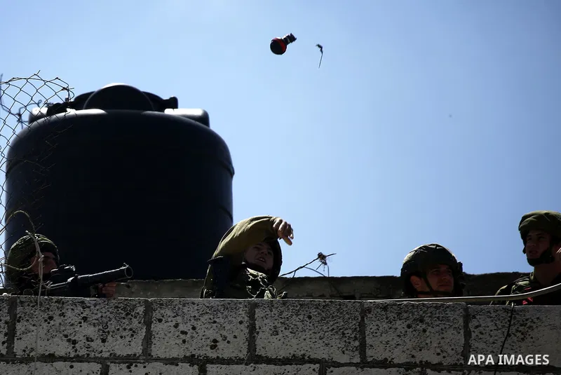 An Israeli soldier throws a tear gas canister during clashes with Palestinian protesters on March 31, 2018 in occupied West Bank city of Hebron as a general strike is called for by local leaders in solidarity with Gaza....