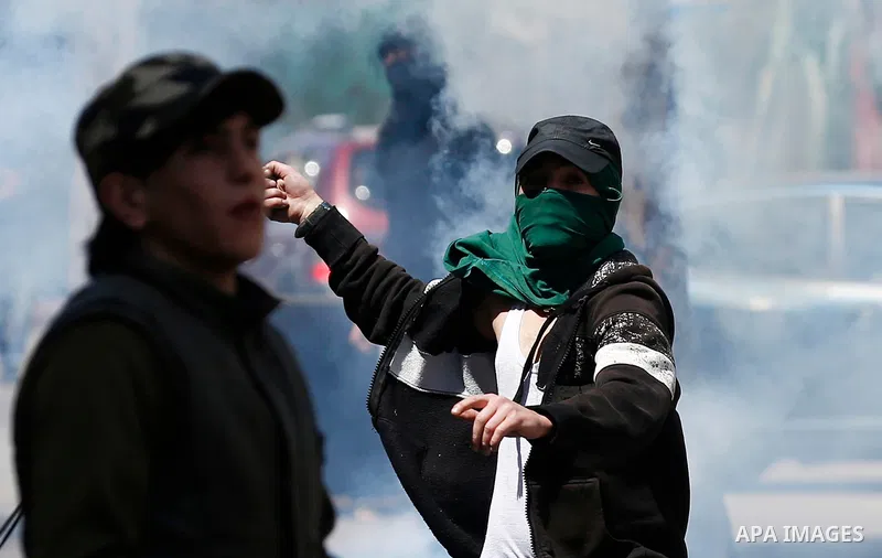 A Palestinian protester uses a slingshot to throw back a tear gas canister fired by Israeli security forces during clashes on March 31, 2018 in occupied West Bank city of Hebron as a general strike is called for by local...