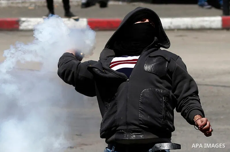A Palestinian protester throws back a tear gas canister fired by Israeli security forces during clashes on March 31, 2018 in occupied West Bank city of Hebron as a general strike is called for by local leaders in solidar...