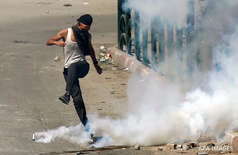 A Palestinian protester kicks back a tear gas canister fired by Israeli security forces during clashes on March 31, 2018 in occupied West Bank city of Hebron as a general strike is called for by local leaders in solidari...