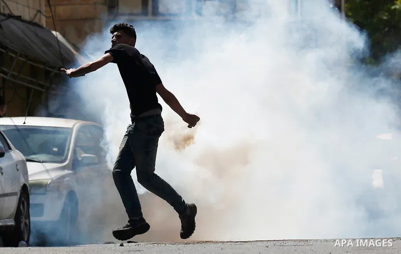 A Palestinian protester throws back a tear gas canister fired by Israeli security forces during clashes on March 31, 2018 in occupied West Bank city of Hebron as a general strike is called for by local leaders in solidar...