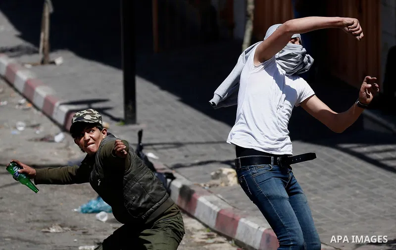 Palestinian protesters throw stones towards Israeli security forces during clashes on March 31, 2018 in occupied West Bank city of Hebron as a general strike is called for by local leaders in solidarity with Gaza. At lea...