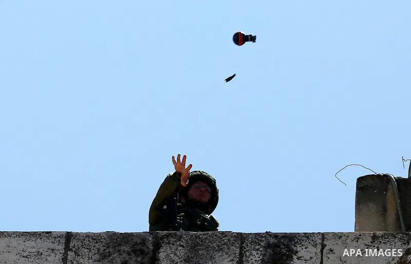 An Israeli soldier throws a tear gas canister during clashes with Palestinian protesters on March 31, 2018 in occupied West Bank city of Hebron as a general strike is called for by local leaders in solidarity with Gaza....