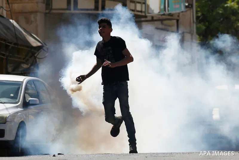 A Palestinian protester throws back a tear gas canister fired by Israeli security forces during clashes on March 31, 2018 in occupied West Bank city of Hebron as a general strike is called for by local leaders in solidar...