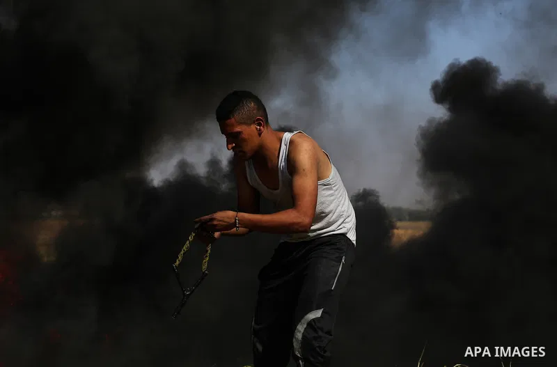 An injured Palestinian woman is carried by protesters as they run for cover during a protest along the border with Israel, east of Khan Yunis, in the southern Gaza Strip on March 31, 2018. The UN Security Council heard f...