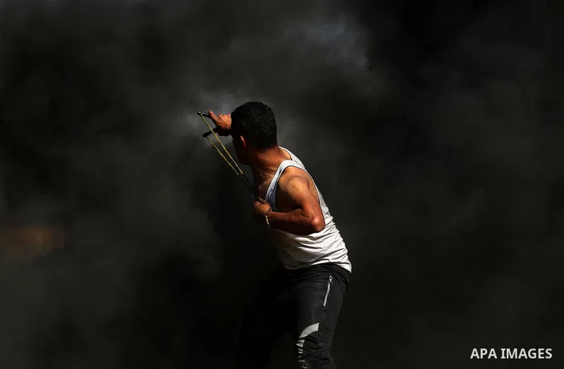 A Palestinian protester hurls stones toward Israeli soldiers during a protest along the border with Israel, east of Khan Yunis, in the southern Gaza Strip on March 31, 2018. The UN Security Council heard fears of a furth...