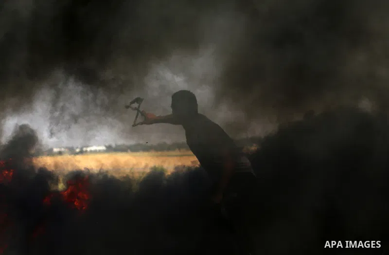 A Palestinian protester hurls stones toward Israeli soldiers during a protest along the border with Israel, east of Khan Yunis, in the southern Gaza Strip on March 31, 2018. The UN Security Council heard fears of a furth...