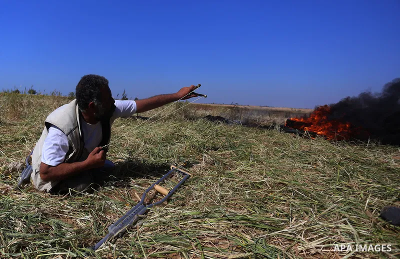 A Palestinian protester hurls stones toward Israeli soldiers during a protest along the border with Israel, east of Khan Yunis, in the southern Gaza Strip on March 31, 2018. The UN Security Council heard fears of a furth...