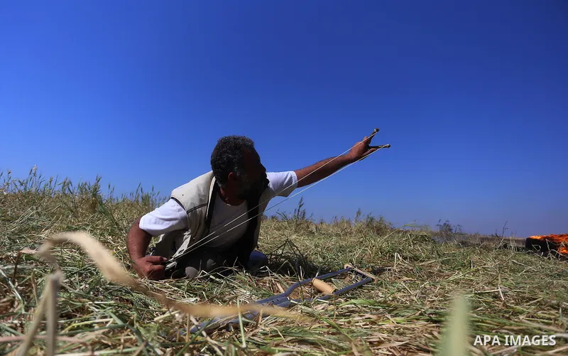 A Palestinian protester hurls stones toward Israeli soldiers during a protest along the border with Israel, east of Khan Yunis, in the southern Gaza Strip on March 31, 2018. The UN Security Council heard fears of a furth...