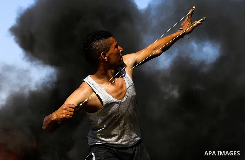 A Palestinian protester hurls stones toward Israeli soldiers during a protest along the border with Israel, east of Khan Yunis, in the southern Gaza Strip on March 31, 2018. The UN Security Council heard fears of a furth...