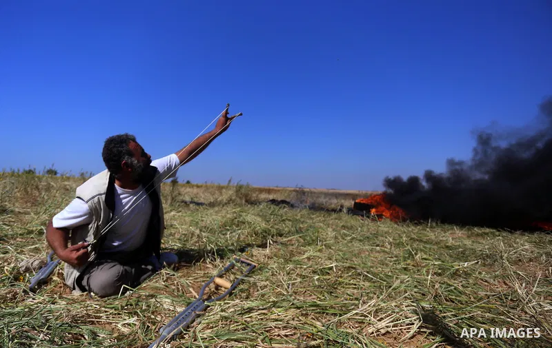 A Palestinian protester hurls stones toward Israeli soldiers during a protest along the border with Israel, east of Khan Yunis, in the southern Gaza Strip on March 31, 2018. The UN Security Council heard fears of a furth...