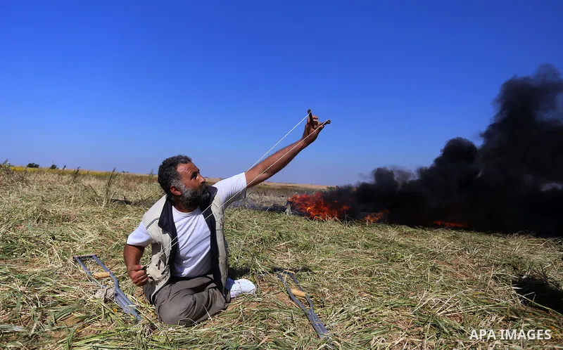 A Palestinian protester hurls stones toward Israeli soldiers during a protest along the border with Israel, east of Khan Yunis, in the southern Gaza Strip on March 31, 2018. The UN Security Council heard fears of a furth...