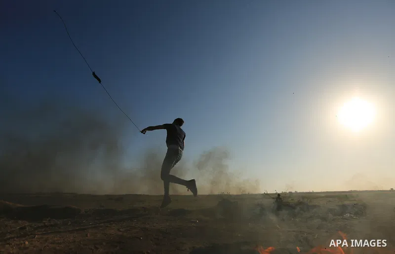 A Palestinian protester hurls stones toward Israeli soldiers during a protest along the border with Israel, east of Gaza City on March 31, 2018. The UN Security Council heard fears of a further escalation in Israeli-Pale...