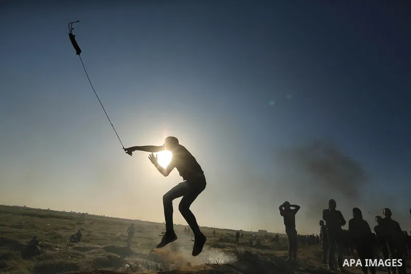 A Palestinian protester hurls stones toward Israeli soldiers during a protest along the border with Israel, east of Gaza City on March 31, 2018. The UN Security Council heard fears of a further escalation in Israeli-Pale...