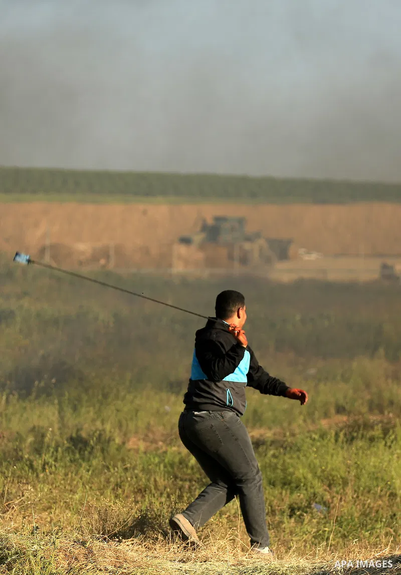 A Palestinian protester hurls stones toward Israeli soldiers during a protest along the border with Israel, east of Gaza City on March 31, 2018. The UN Security Council heard fears of a further escalation in Israeli-Pale...