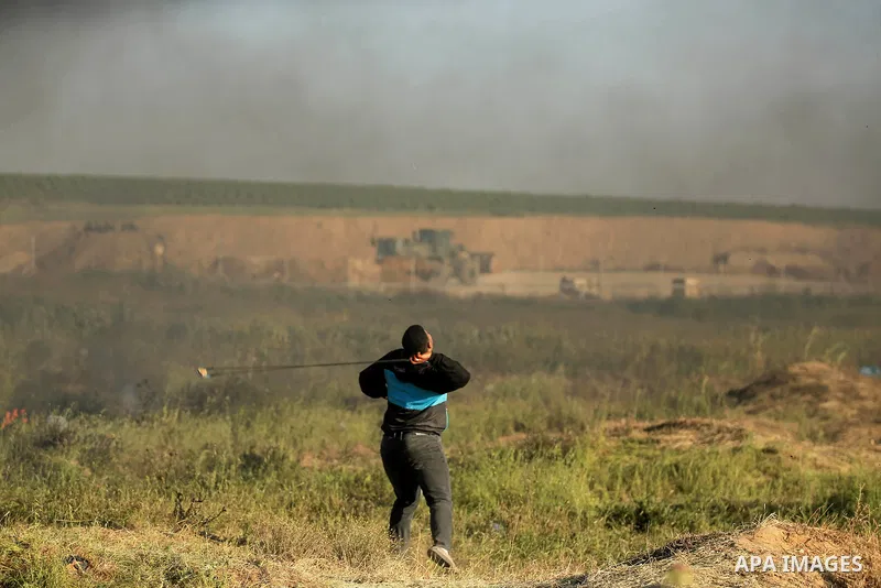A Palestinian protester hurls stones toward Israeli soldiers during a protest along the border with Israel, east of Gaza City on March 31, 2018. The UN Security Council heard fears of a further escalation in Israeli-Pale...