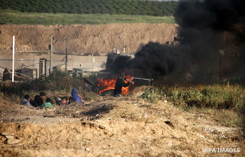 A Palestinian youth swings a slingshot during clashes with Israeli security forces in a protest, at the Israel-Gaza border, demanding the right to return to their homeland, east of Gaza City April 1, 2018. Photo by Mahmo...
