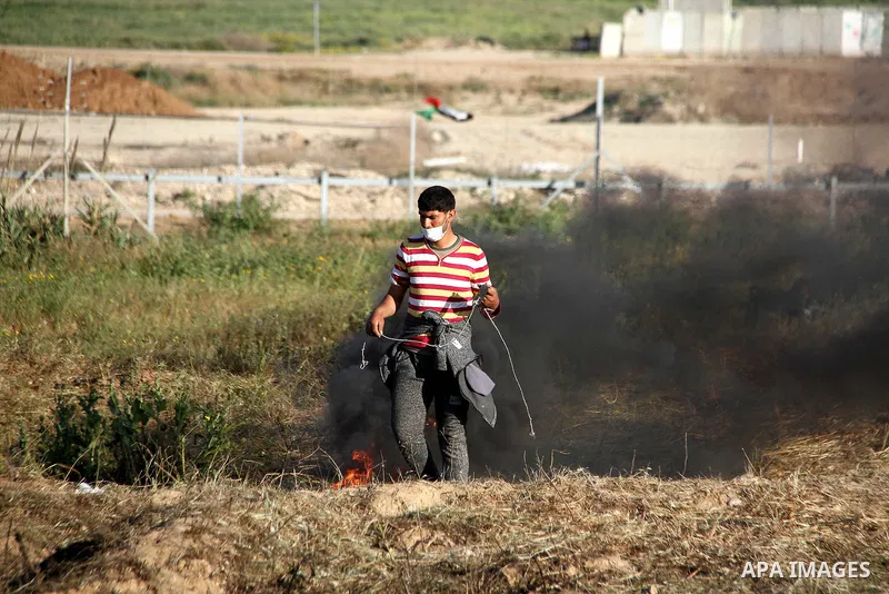 A Palestinian youth swings a slingshot during clashes with Israeli security forces in a protest, at the Israel-Gaza border, demanding the right to return to their homeland, east of Gaza City April 1, 2018. Photo by Mahmo...
