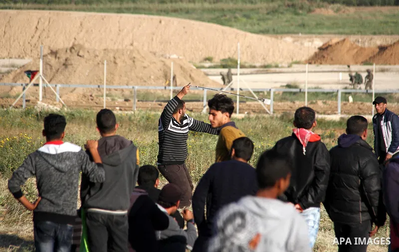 A Palestinian youth swings a slingshot during clashes with Israeli security forces in a protest, at the Israel-Gaza border, demanding the right to return to their homeland, east of Gaza City April 1, 2018. Photo by Mahmo...