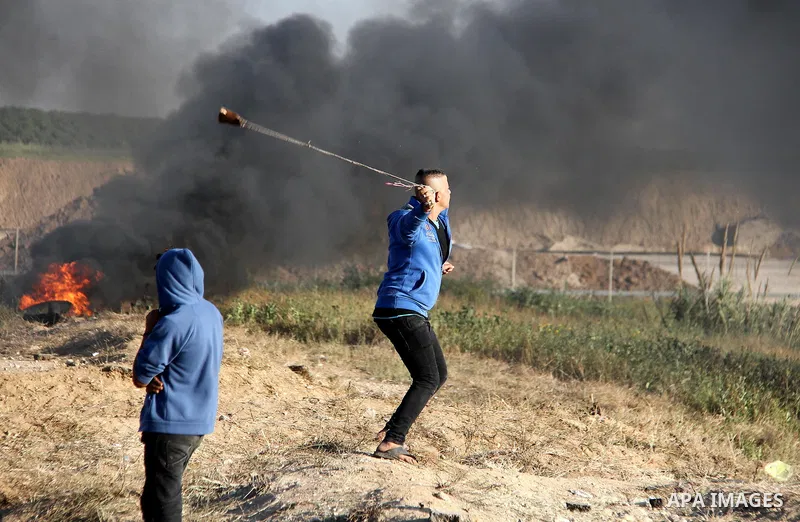 A Palestinian youth swings a slingshot during clashes with Israeli security forces in a protest, at the Israel-Gaza border, demanding the right to return to their homeland, east of Gaza City April 1, 2018. Photo by Mahmo...