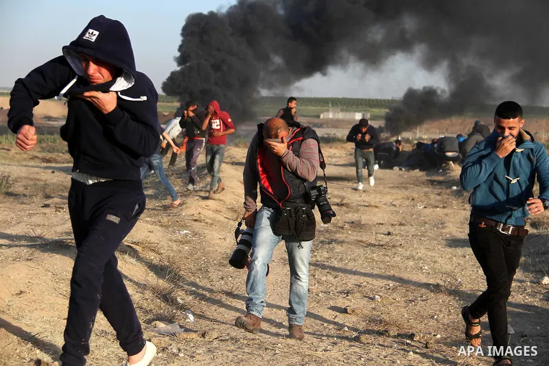 A Palestinians journalist reacts from tear gas, fired by Israeli security forces during clashes in a protest, at the Israel-Gaza border, demanding the right to return to their homeland, east of Gaza City April 1, 2018. P...