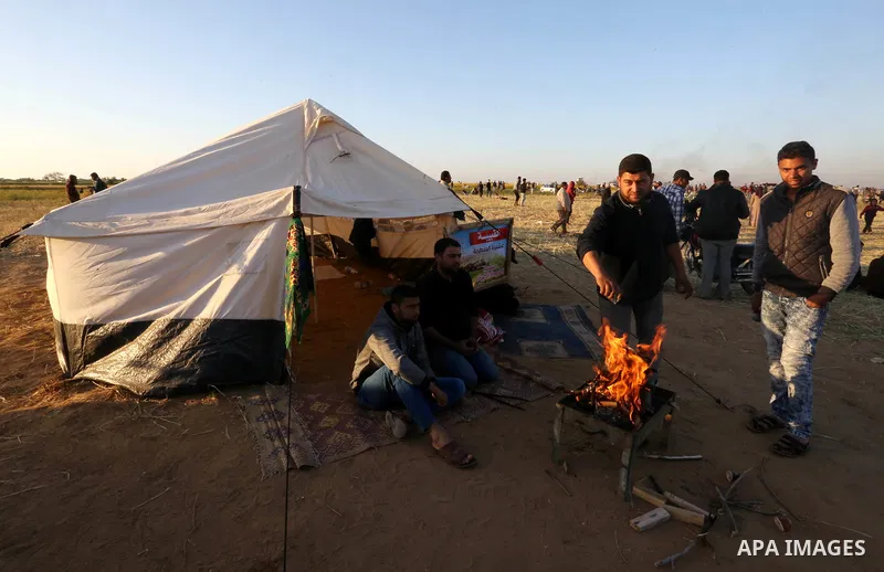Palestinians sit next to a tent during a protest, at the Israel-Gaza border, demanding the right to return to their homeland, in Khan Younis in the southern Gaza strip on April 1, 2018. Photo by Ashraf Amra