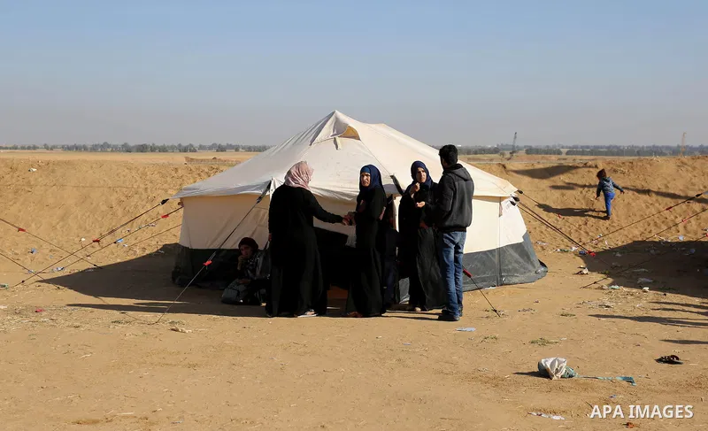 Palestinians sit next to tents during a protest, at the Israel-Gaza border, demanding the right to return to their homeland, in Khan Younis in the southern Gaza strip on April 1, 2018. Photo by Ashraf Amra