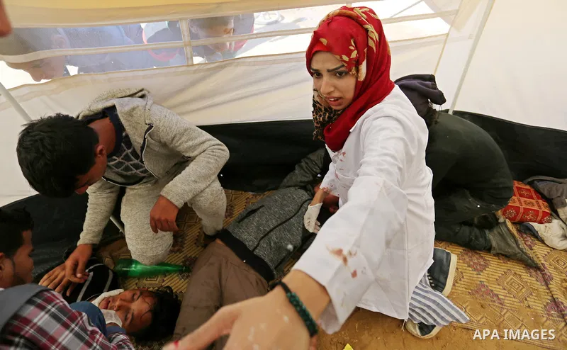 Palestinian medical Razan al-Najjar helps an injured Palestinian man at an emergency medical tent during clashes with Israeli security forces in a protest, at the Israel-Gaza border, demanding the right to return to thei...