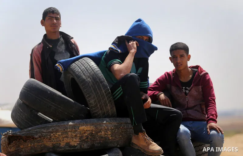 Palestinian protesters collect tires during a tent city protest at the Israel-Gaza border, in Khan Yunis in the southern Gaza Strip, on April 2, 2018. Photo by Yasser Qudih