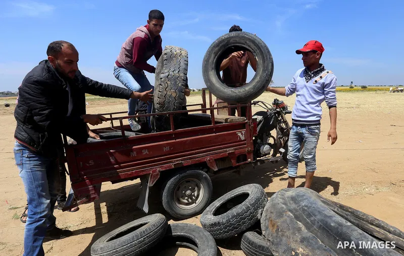 Palestinian protesters collect tires during a tent city protest at the Israel-Gaza border, in Khan Yunis in the southern Gaza Strip, on April 2, 2018. Photo by Yasser Qudih