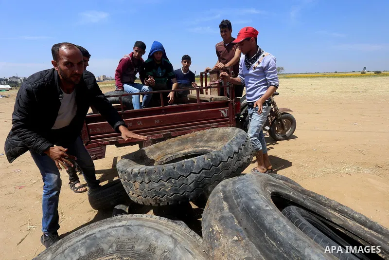 Palestinian protesters collect tires during a tent city protest at the Israel-Gaza border, in Khan Yunis in the southern Gaza Strip, on April 2, 2018. Photo by Yasser Qudih