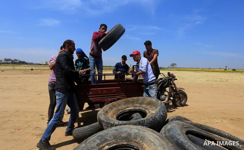 Palestinian protesters collect tires during a tent city protest at the Israel-Gaza border, in Khan Yunis in the southern Gaza Strip, on April 2, 2018. Photo by Yasser Qudih