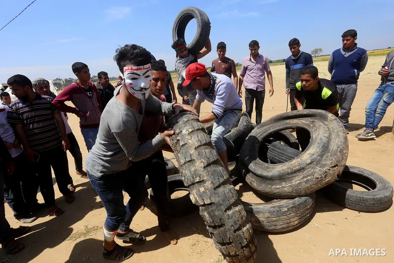 Palestinian protesters collect tires during a tent city protest at the Israel-Gaza border, in Khan Yunis in the southern Gaza Strip, on April 2, 2018. Photo by Yasser Qudih