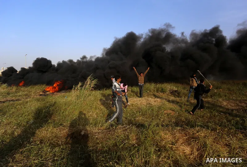 Palestinian protesters use a slingshot to hurl stones towards Israeli security forces during clashes in a tent city protest along the Israel border with Gaza, demanding the right to return to their homeland, in east of G...