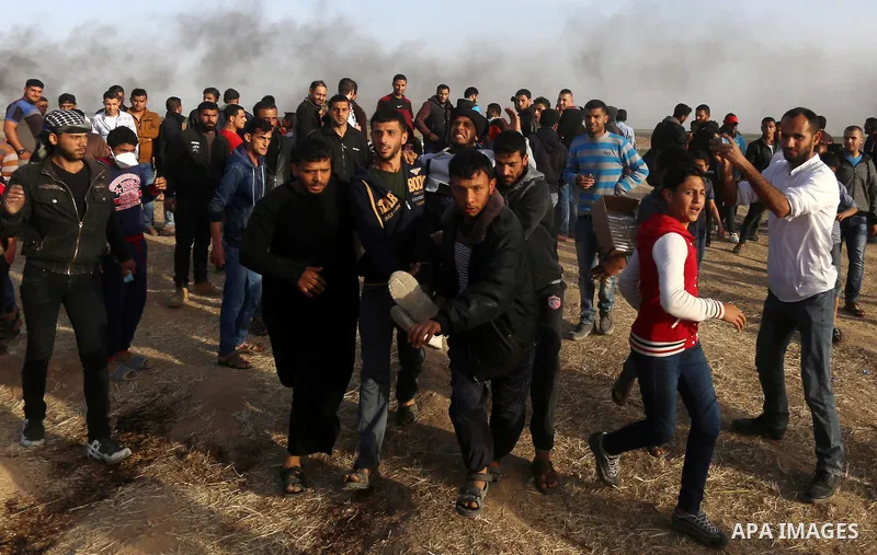 Palestinian protesters carry a man injured during clashes with Israeli security forces in a tent city protest along the Israel border with Gaza, demanding the right to return to their homeland, in east of Gaza city on Ap...